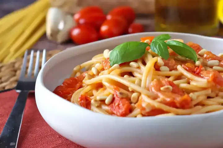 Spaghetti con pomodorini, pinoli e basilico, un'idea per sughi estivi per pasta freschi e veloci.