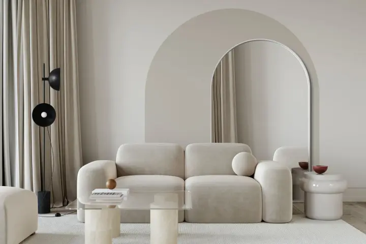 Nowoczesny salon z beżową kanapą, łukiem nad lustrem i stolikiem kawowym. Inspiracja, jak zrobić łuk w aranżacji wnętrz.