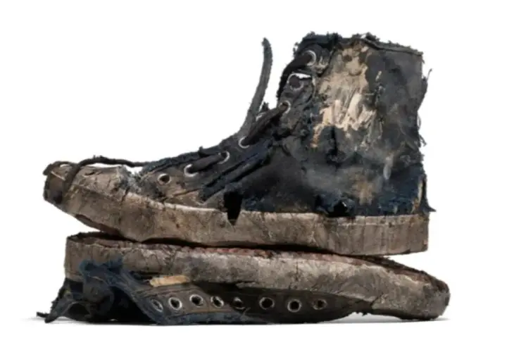 Un par de zapatillas gastadas, rotas y sucias, apiladas una sobre otra. Parecen haber vivido muchas aventuras.