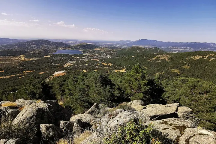 Vista panorámica del valle de la barranca, con un lago azul y montañas verdes bajo un cielo despejado.