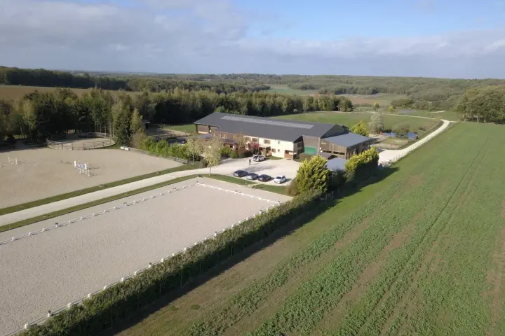Vue aérienne d'une écurie avec manège et carrière de dressage. Le système de **carrière subirrigation** assure un sol parfait pour les chevaux.