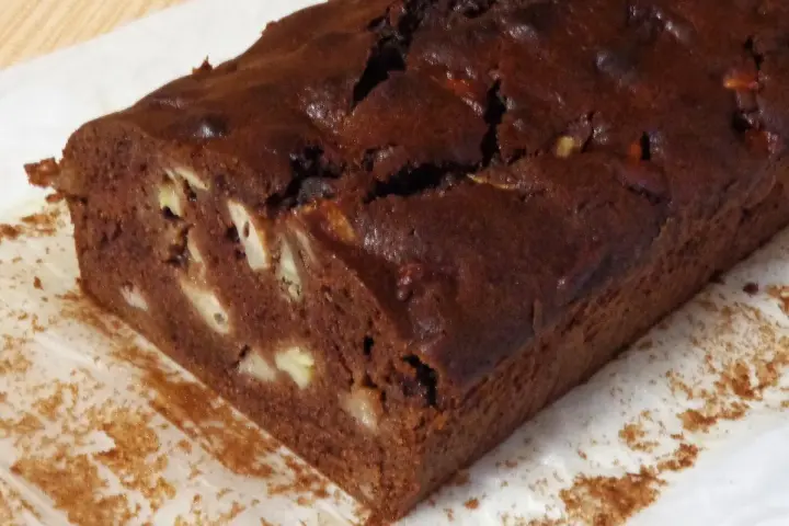 Wilgotne ciasto czekoladowe z bananami, z widocznymi kawałkami owoców w środku.