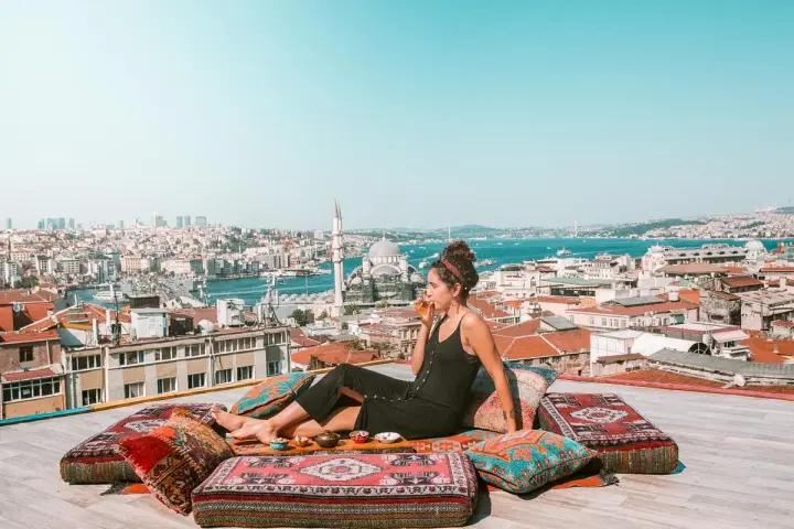 A woman enjoys a drink on a rooftop overlooking Istanbul, a scene straight out of a Rick Steves Turkey adventure.