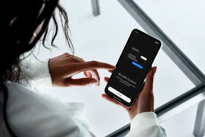 En person håller en smartphone som visar en chattapp. Enkel design för att skapa sms grupp iphone och android.