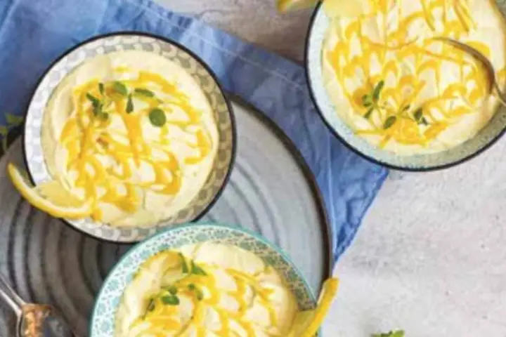 Tre coppette di deliziosa mousse al limone, guarnite con scorza di limone e menta fresca.
