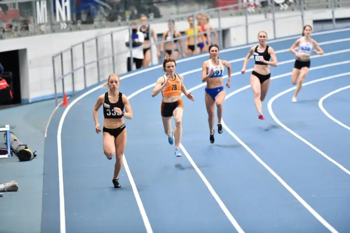 Aneta Lemiesz biegnie w zawodach lekkoatletycznych, walcząc o zwycięstwo na bieżni.