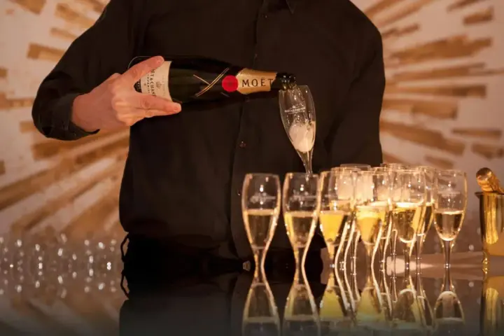 Kelner nalewa szampan Moët & Chandon do kieliszków, przygotowując się do wesela.