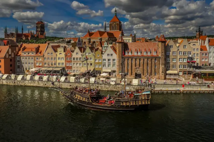 Żaglowiec na Motławie przed kolorowymi kamieniczkami w Gdańsku.