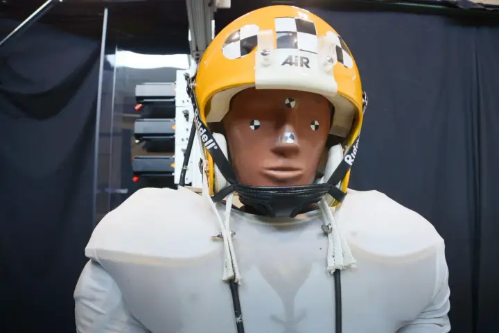 Manichino con casco giallo e bianco, con segni di misurazione, pronto per testare come capire se un casco è omologato.