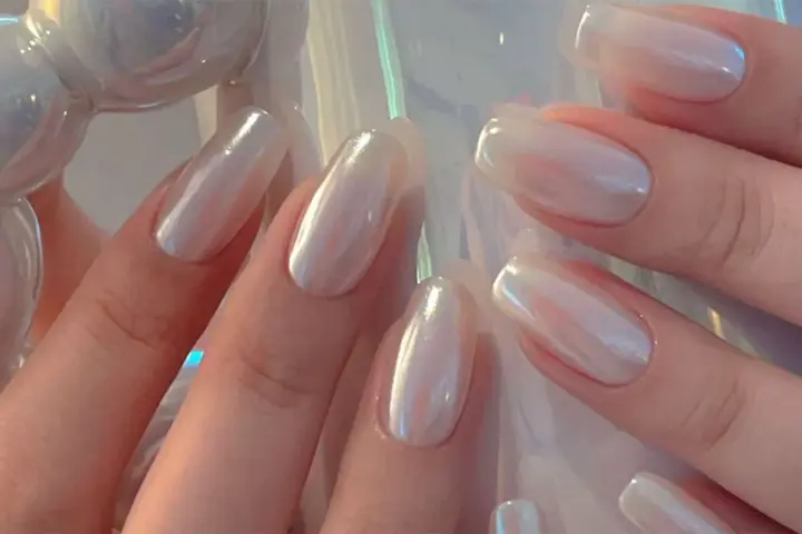 Mani eleganti con unghie a specchio perlate, che riflettono la luce con un effetto iridescente e sofisticato.