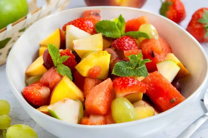 Ein bunter Obstsalat mit Erdbeeren, Melone, Pfirsich und Trauben – ein einfaches obstsalat rezept für heiße Tage.