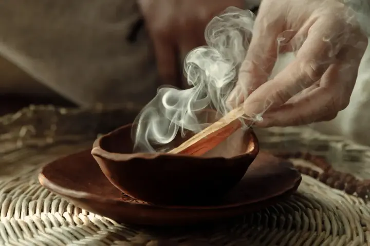 Dym z kadzidła palo santo unosi się z glinianej miseczki. Poznaj, jak palić palo santo, by oczyścić przestrzeń.