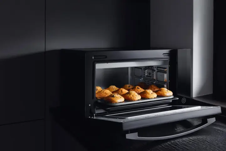 Horno de leña empotrado con bandeja de muffins recién horneados.