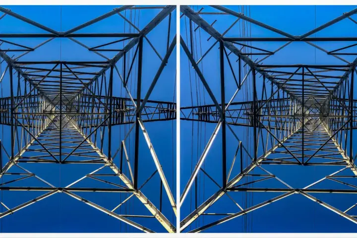 Widok z dołu na kratownicę słupa energetycznego, tworzącą geometryczny wzór na tle błękitnego nieba. To fotografia stereoskopowa.
