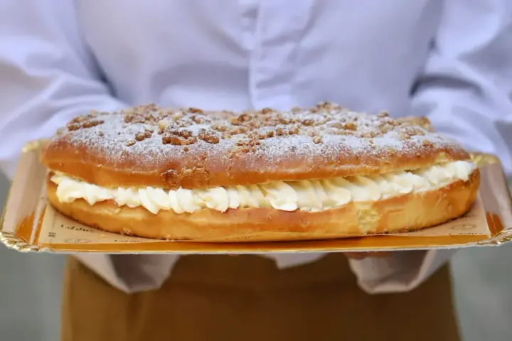Deliciosa coca de San Juan rellena de crema, cubierta con azúcar glas y trocitos crujientes. ¡Perfecta para celebrar!