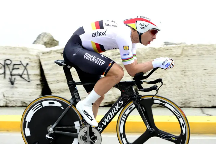 Cyclist in full aerodynamic gear, focused on time trial training, pushing hard on a specialized bike.
