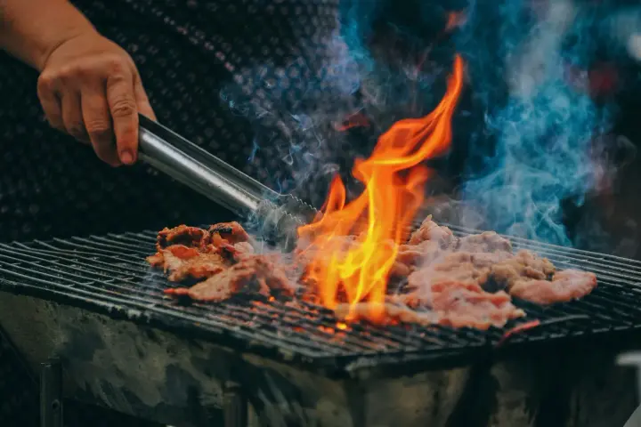 Carne a la parrilla, humeante y chispeante, lista para una deliciosa parrillada barbacoa.