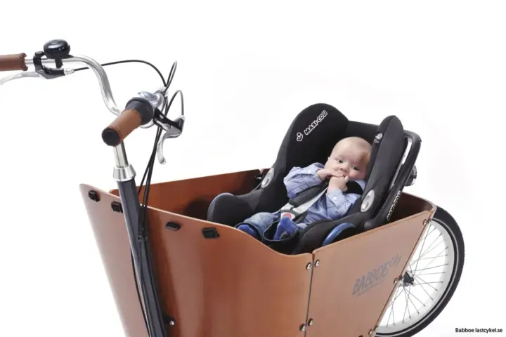 En bebis sitter tryggt i en bilbarnstol monterad i en lastcykel. Perfekt för att cykla med bebis på ett säkert och bekvämt sätt.