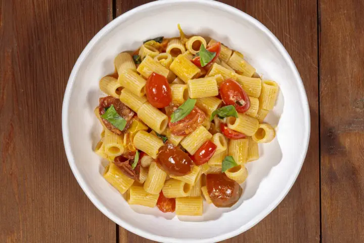 Un piatto invitante di pasta con pomodorini freschi, basilico e un filo d'olio.