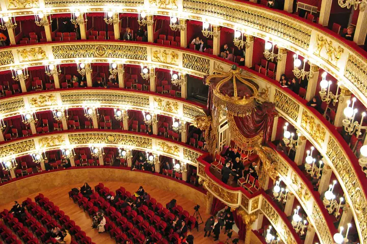 Elegancka loża w teatrze, z czerwonymi aksamitnymi siedzeniami i złotymi zdobieniami, czeka na widzów.
