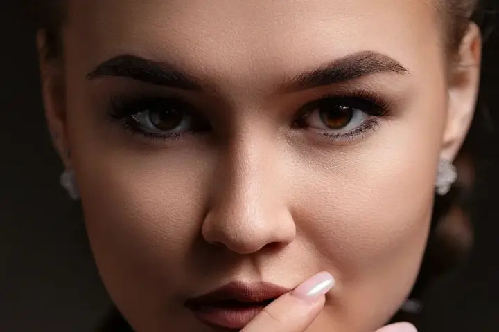 Un gros plan sur le visage d'une femme, ses sourcils parfaitement dessinés après une séance d'épilation.
