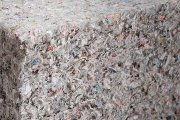 Materiały budowlane: celuloza ocieplenie z recyklingu, tworzące zwartą, włóknistą strukturę z kolorowymi fragmentami.