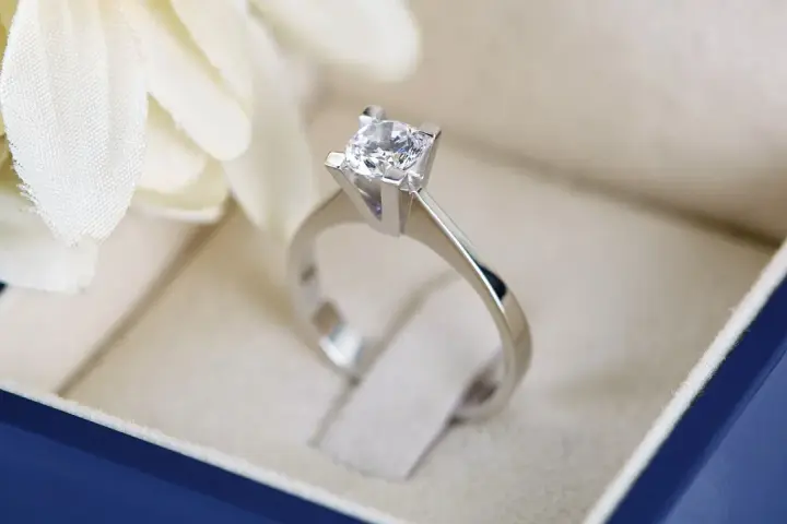 Anello con diamante in un cofanetto blu. La brillantezza del diamante, misurata in carati, cattura la luce.