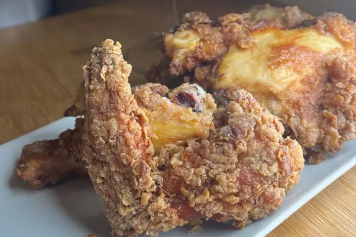 Pollo fritto croccante, un chrusty przepis che fa venire l'acquolina in bocca. Pezzi dorati e succulenti su un piatto bianco.