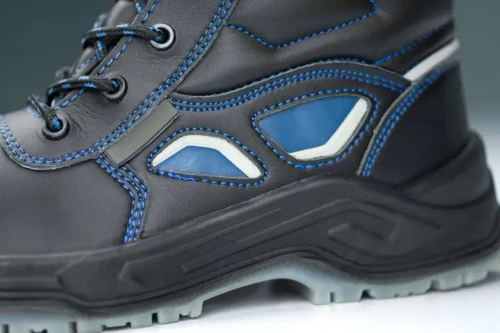 Bota de trabajo negra con costuras azules y detalles en azul y blanco. La suela tpu ofrece agarre y durabilidad para cualquier terreno.