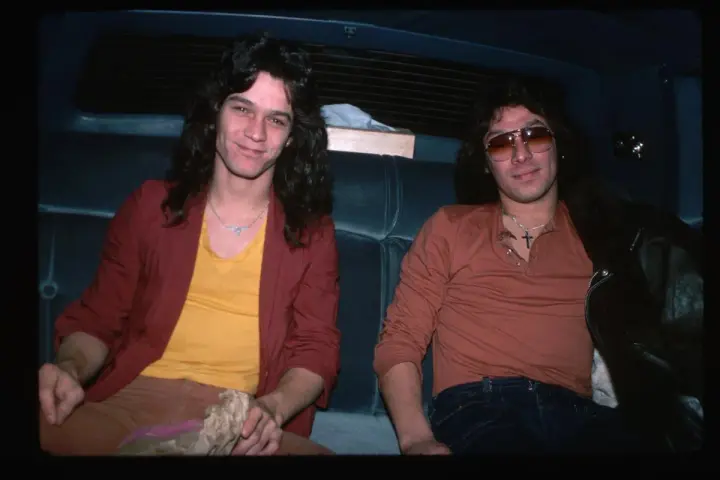 Alex Van Halen i jego brat Eddie Van Halen siedzą w samochodzie, obaj w stylowych ubraniach z lat 80.