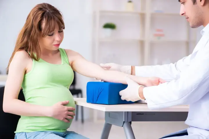 Lekarz pobiera krew od ciężarnej kobiety, aby sprawdzić poziom glukozy w ciąży.