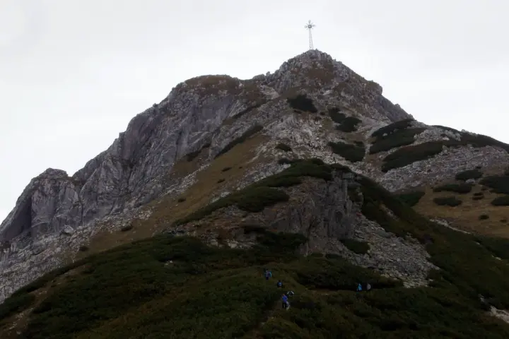 Wspinaczka na Giewont. Grupa turystów pokonuje skaliste zbocze, gdzie w trudniejszych miejscach pomagają łańcuchy.