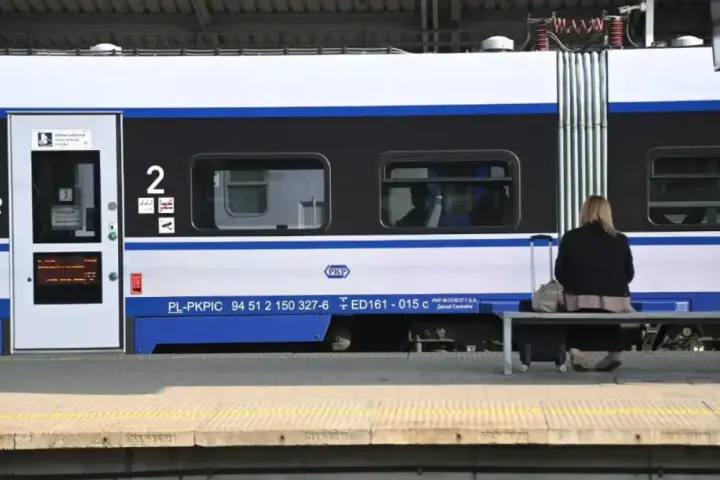 Kobieta z walizką czeka na pociąg PKP Intercity, szukając tanich biletów.
