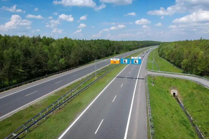 Znaki na autostradzie A4 informują, czy jest ona płatna. Widok na pustą autostradę w słoneczny dzień.