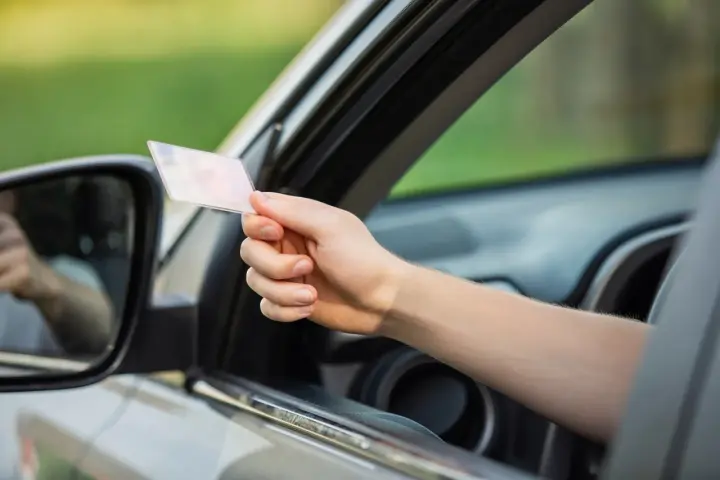 Mano che mostra la patente, in linea con l'articolo 126 bis del codice della strada.