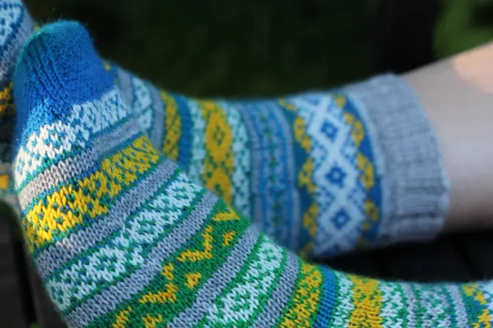 Två par stickade sockor med färgglatt sticka mönster med två färger i blått, gult, grönt och vitt.