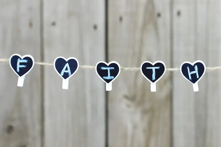 Five heart-shaped clothespins spell "FAITH" on a string, a reminder for prayers for children.
