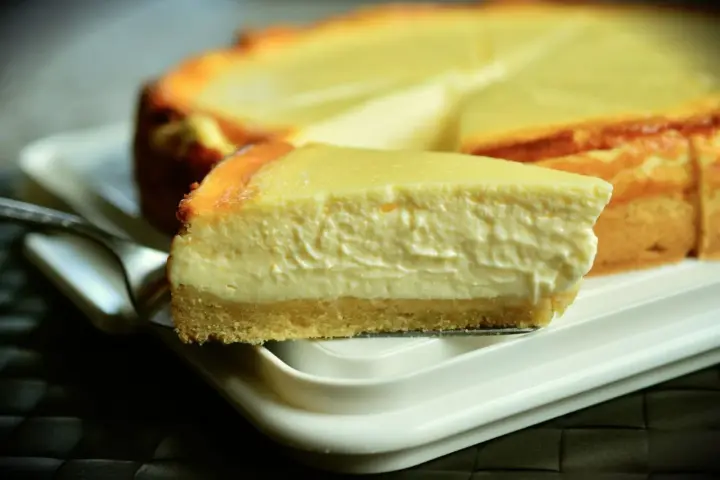 Una rebanada cremosa de tarta de queso Philadelphia, con su base dorada y relleno suave, lista para ser disfrutada.