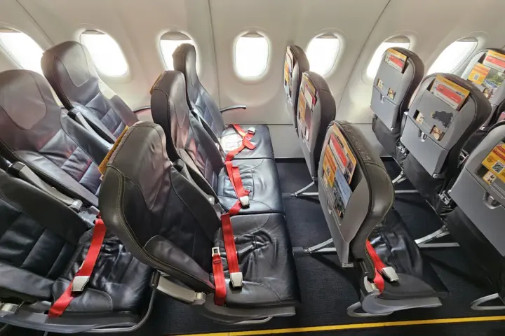 Puste fotele w samolocie, czerwone pasy bezpieczeństwa. Czy warto lecieć Pegasus Airlines? Opinie pasażerów są różne.