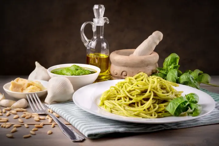 Pyszny makaron z pesto ze słoika, podany z bazylią, czosnkiem, parmezanem i orzeszkami pinii.