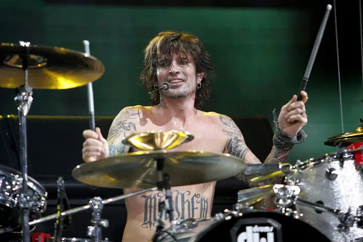 Tommy Lee, batteur du groupe, frappe sur sa batterie, torse nu, tatoué, en plein concert.