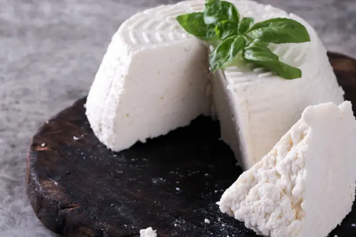 Świeża ricotta z bazylią na ciemnej desce. Idealna do lekkich posiłków, dbając o ricotta kcal.