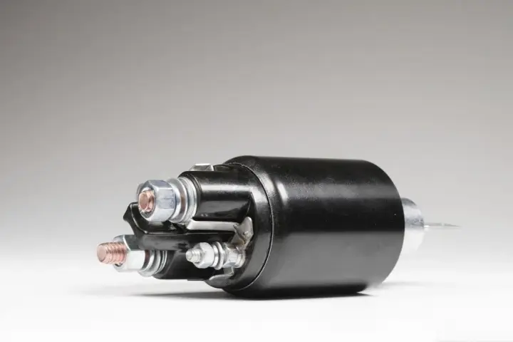 A black starter solenoid with copper and silver bolts, ready to power up an engine.