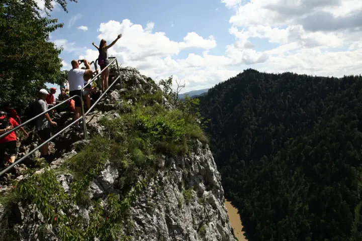 Grupa turystów na skalistym szczycie z widokiem na Pieniny i Dunajec.