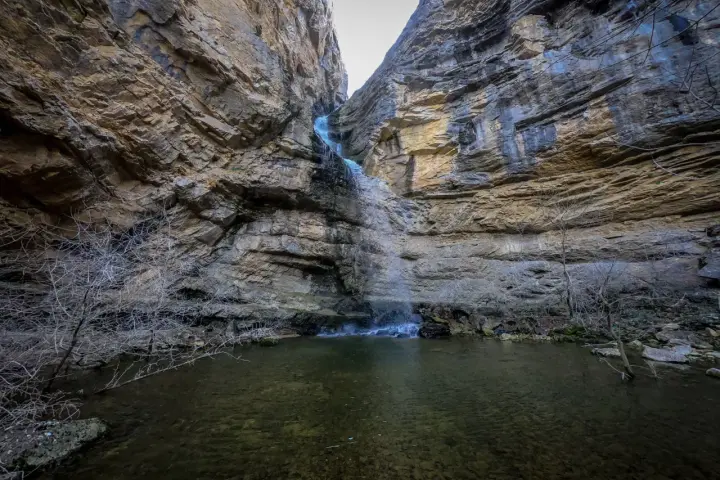 La cascada del Gollorio cae entre imponentes paredes rocosas, formando un estanque sereno.