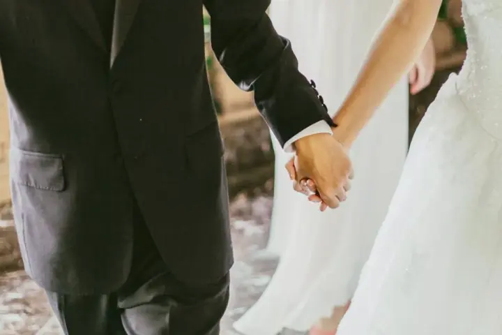 Mani intrecciate, un uomo in abito scuro e una sposa in bianco. Il vero significato di sposa è l'amore che unisce.