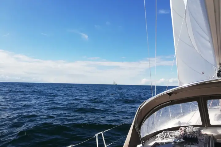 Segeln in Deutschland: Ein Segelboot gleitet über das Meer, im Hintergrund ein weiterer Segler unter blauem Himmel.
