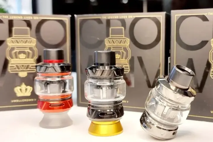 Tres atomizadores Uwell Crown V en rojo, negro y plateado, con sus cajas de fondo.