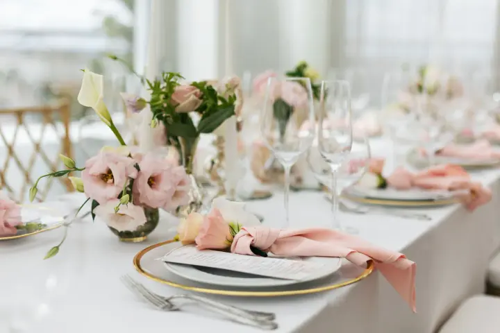 Ett vackert dukat bord med rosa dekorationer, blommor och glas. En elegant dukning för ett speciellt tillfälle.