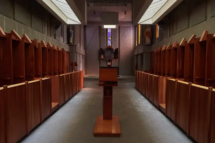 Rows of wooden stalls line the interior of a Carthusian monastery, leading towards an altar.
